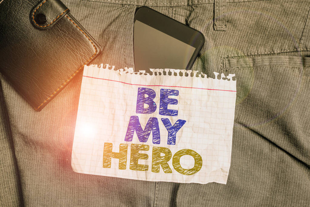 Текст написання слів "Будь моїм героєм". Бізнес-концепція для запиту когось, щоб отримати деякі зусилля героїчних дій для нього смартфон пристрій всередині штанів передня кишеня з гаманцем і нотатки паперу
. - Фото, зображення