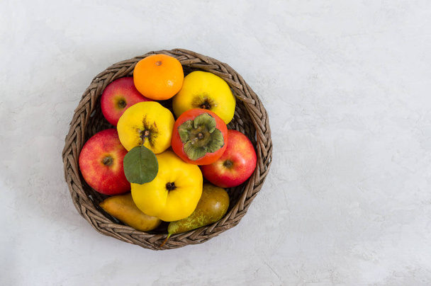 Obstkorb auf hellem Betongrund. Saisonale Früchte sind eine Quelle von Vitaminen und Gesundheit. Kopierraum. - Foto, Bild