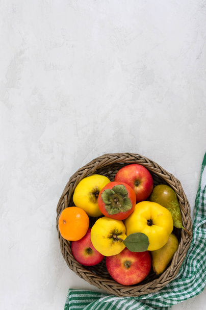 Fruit basket on a light concrete background. Seasonal fruits are a source of vitamins and health. Copy space. - Foto, Imagem