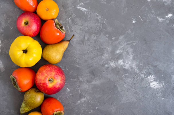 Different seasonal fruits on a concrete background. Source of vitamins and health. Healthy eating concept. Copy space. - Photo, Image