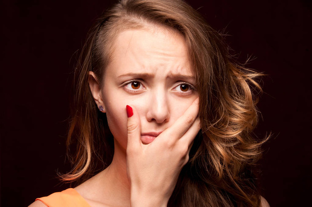 Closeup of girl experiencing a toothache, on a dark background. - Foto, Imagen