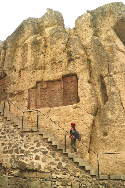 Nő a lépcsőn számos kachkar vagy kereszt-kövek a sziklafal, Geghard kolostor, Örményország - Fotó, kép