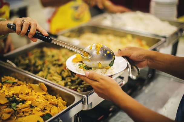 O conceito de fome: Voluntários atraem alimentos para doar a pessoas famintas com preocupação
. - Foto, Imagem