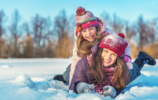 Active mother and daughter playing in winter park - Foto, Bild