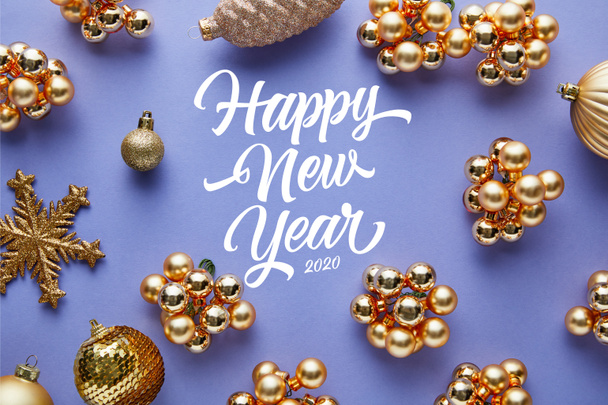 top view of shiny golden Christmas decoration on blue background with happy new year lettering - 写真・画像