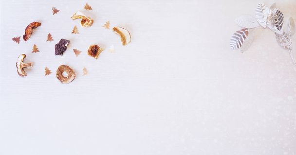 Christmas background: dried mushrooms, silver leafs, decorative Christmas trees on white wood and snow. - Photo, Image