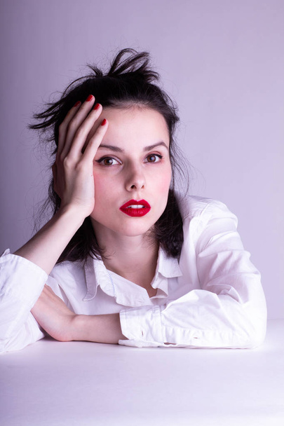 beautiful young girl in a white shirt on a white background with red lipstick on her lips - Valokuva, kuva