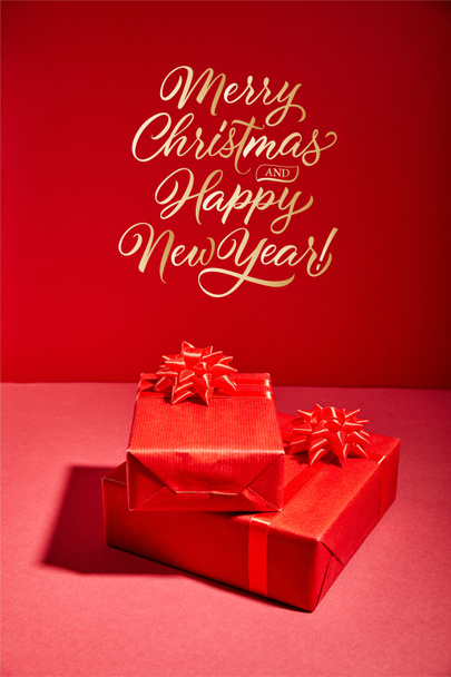 red Christmas gift boxes on red background with golden Merry Christmas and happy new year illustration - Zdjęcie, obraz