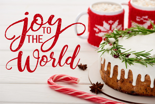 cana-de-açúcar, torta de Natal com cobertura e duas xícaras de cacau com marshmallows na mesa de madeira branca com alegria para a ilustração do mundo
 - Foto, Imagem