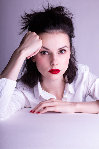 beautiful young girl in a white shirt on a white background with red lipstick on her lips - Foto, Imagem