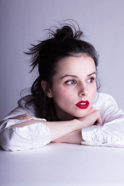 beautiful young girl in a white shirt on a white background with red lipstick on her lips - Photo, image