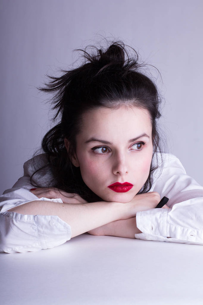 beautiful young girl in a white shirt on a white background with red lipstick on her lips - Foto, imagen