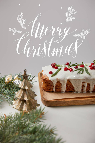 traditional Christmas cake with cranberry near baubles and pine on white table isolated on grey with Merry Christmas illustration - Photo, image