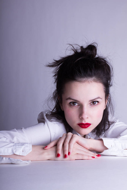 beautiful young girl in a white shirt on a white background with red lipstick on her lips - Fotó, kép