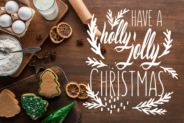 top view of delicious Christmas cookies near ingredients and spices on wooden table with have a holly jolly Christmas lettering - 写真・画像