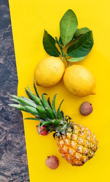 Fresh ripe exotic fruits with leaves on the yellow background - Photo, Image