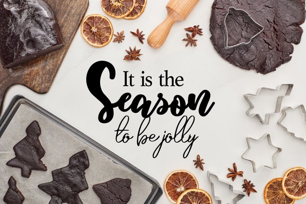 vista dall'alto di pasta cruda per biscotti di Natale al cioccolato vicino ingredienti su sfondo bianco con esso è la stagione di apice lettering allegro
 - Foto, immagini