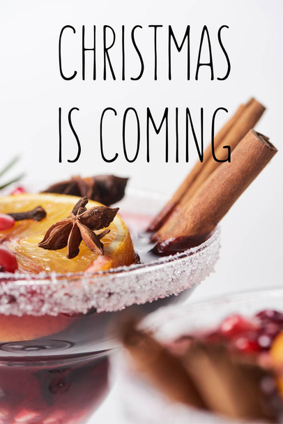 selective focus of christmas cocktail with orange, pomegranate, cinnamon with christmas is coming illustration  - Photo, Image