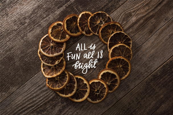 round frame of dried orange slices on wooden background with all is fun all is bright lettering - Foto, imagen