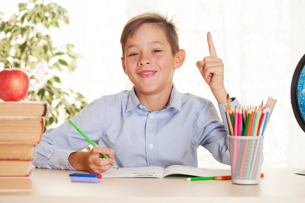 Young schoolboy sitting at the table and doing homework. Elementary education concept - Photo, Image