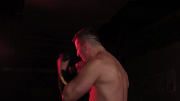 Atlétikai férfi boksz súlyzókkal piros világításban. - Felvétel, videó