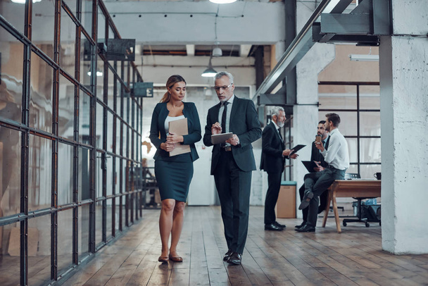 Teljes hossza két kolléga elegáns formális viselet megvitatása üzleti séta közben az irodateremben - Fotó, kép