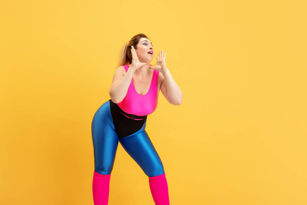 Young caucasian plus size female models training on yellow background - Foto, immagini