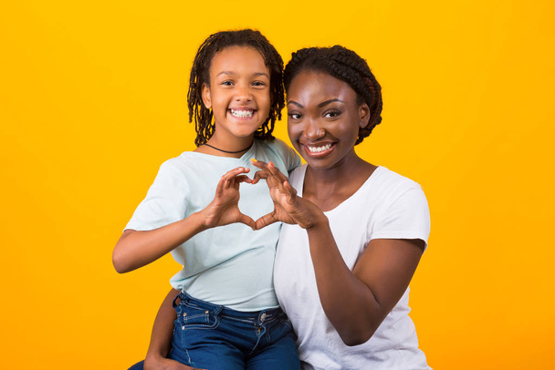 lächelnde Afro-Frau und Mädchen, die Herzform Zeichen - Foto, Bild