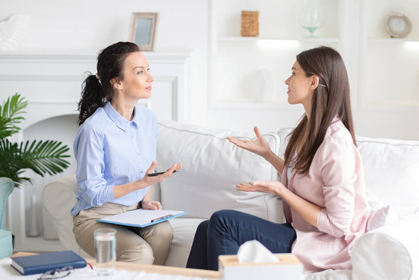 Female patient and psychotherapist having emotional conversation - 写真・画像