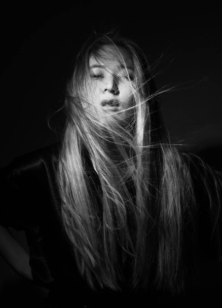 Portrait of a blonde in black clothes on a black background. - Foto, afbeelding