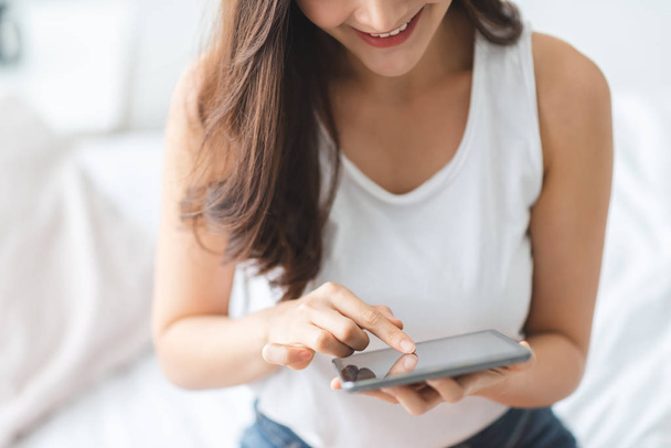 Smiling Asian woman using digital tablet computer while relaxing - Foto, Bild