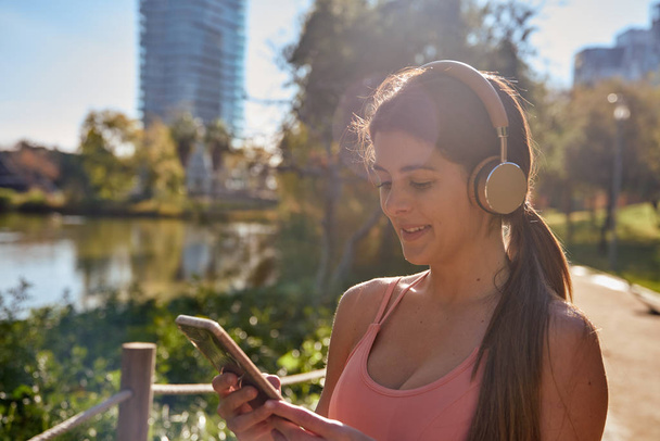 Woman looking at a cell phone wearing headphones - Foto, Imagen