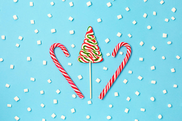 Canne à bonbons de Noël et arbre de Noël avec guimauves sur fond bleu
. - Photo, image