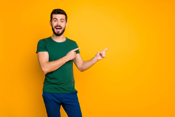 Portrait of excited crazy guy promoter look incredible discounts information scream wow omg indicate adverts promo point index finger copyspace wear blue pants isolated yellow color background - Zdjęcie, obraz
