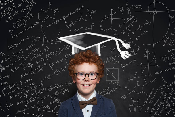 Niño feliz con sombrero de graduación, gafas y uniforme de estudiante
  - Foto, Imagen