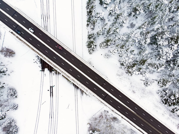 Kaunis ilmakuva lumen peittämille pelloille, joissa on kaksikaistainen tie puiden keskellä. Kohtalainen talvimaisema Vilnan lähellä, Liettua
. - Valokuva, kuva