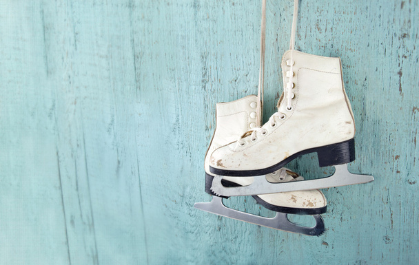 Women's ice skates hanging on blue wooden background - Photo, Image