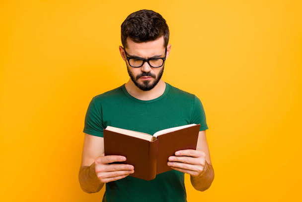 Portrait of focused college student guy hold read textbook learn information for study project wear spectacles good looking clothes isolated over yellow color background - Zdjęcie, obraz