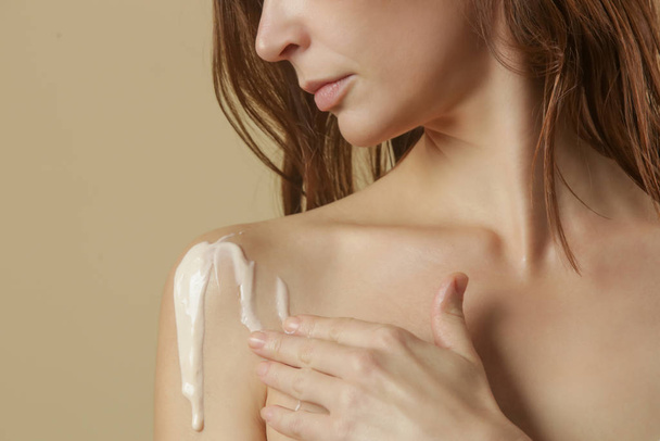 Mulher aplicando creme corporal no braço, conceito de cuidados com a pele de beleza, tiro estúdio
 - Foto, Imagem