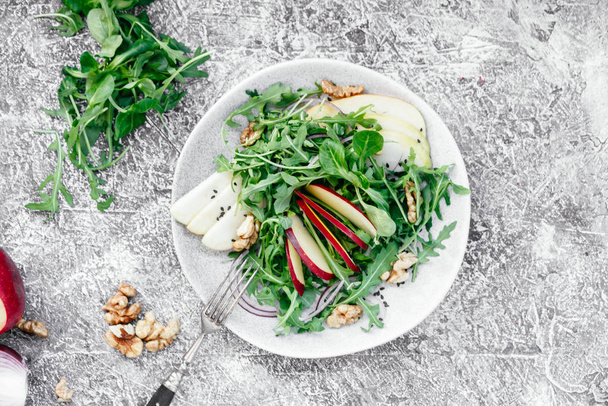 Vegetarian salad of fresh apples with arugula, onions and nuts in a plate on the table - Fotografie, Obrázek