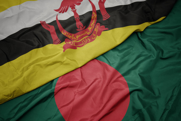 Bangladeş 'in renkli bayrağını sallıyor ve ulusal brunei bayrağını sallıyor.. - Fotoğraf, Görsel