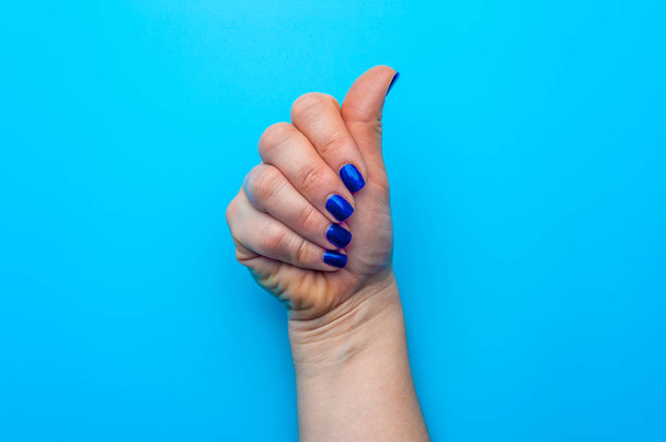Female hand with dark blue nails showing gesture - 写真・画像