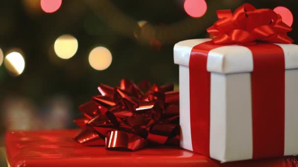 Yılbaşı hediye kutuları çok renkli Noel ağacı ışıkları arka planında - Video, Çekim
