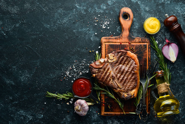T-bone steak grilled with rosemary and spices. Top view. Free space for your text. - Foto, afbeelding