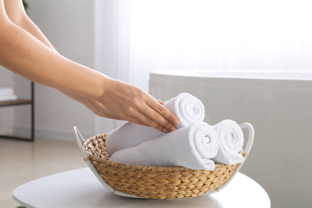 Woman putting soft towels in basket - 写真・画像