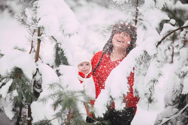 Portrait of happy little girl in red coat with dad having fun with snow in winter forest. girl playing with dad - Фото, зображення