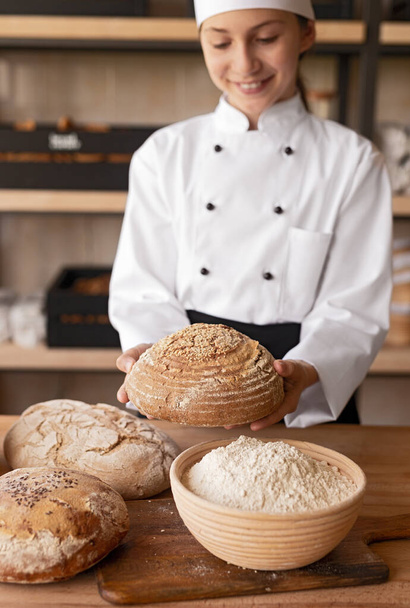 Little baker showing loaf of bread - Foto, imagen