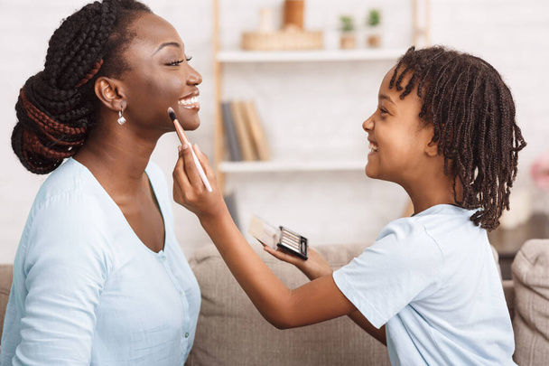 Afro-Amerikaanse dochter doet make-up voor moeder - Foto, afbeelding