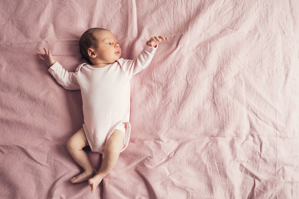 Un neonato è sdraiato su uno sfondo rosa in una t-shirt rosa
 - Foto, immagini