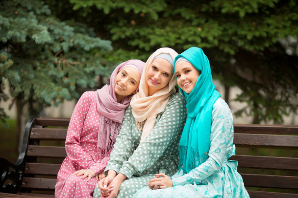 three beautiful young women in muslim dresses in summer at the park - Foto, imagen
